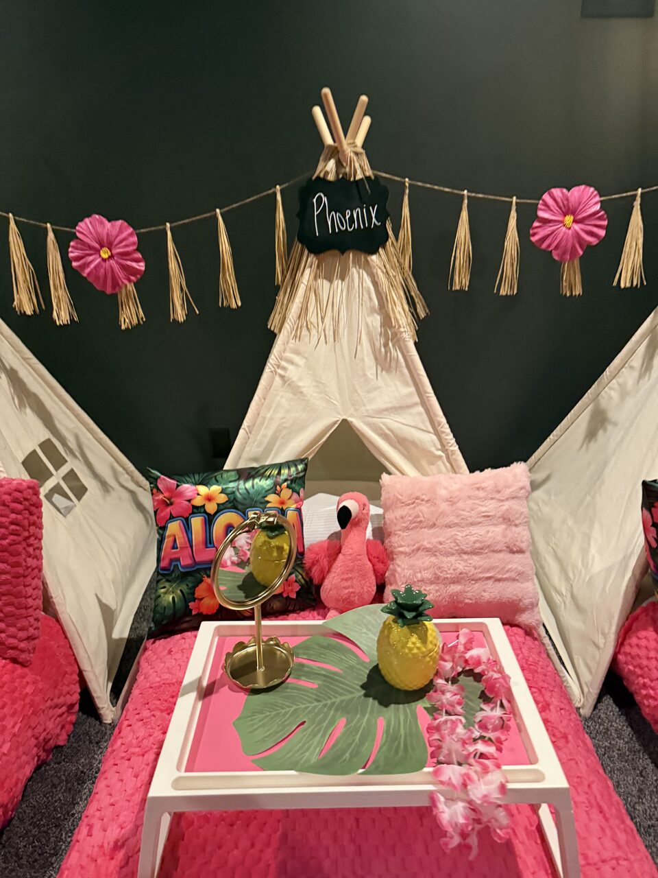 Tropical pink Phoenix birthday teepee with hibiscus flowers, tasseled garland, and Aloha pillows
