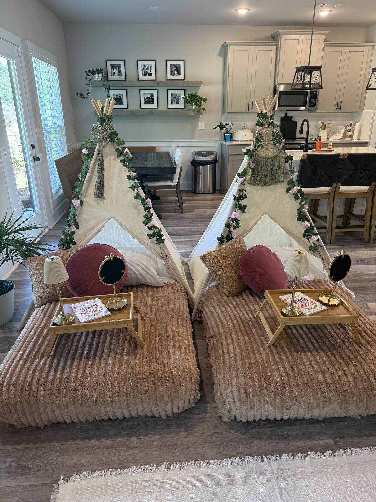 Close-up of a blush teepee bed with pillows, lamp, mirror, and tray