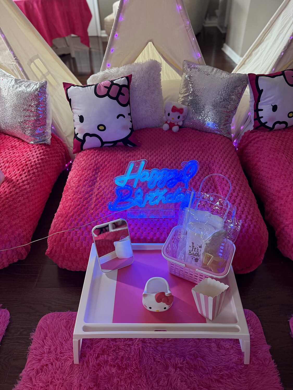 Hello Kitty-inspired birthday teepee with a glowing Happy Birthday sign and pink party favors