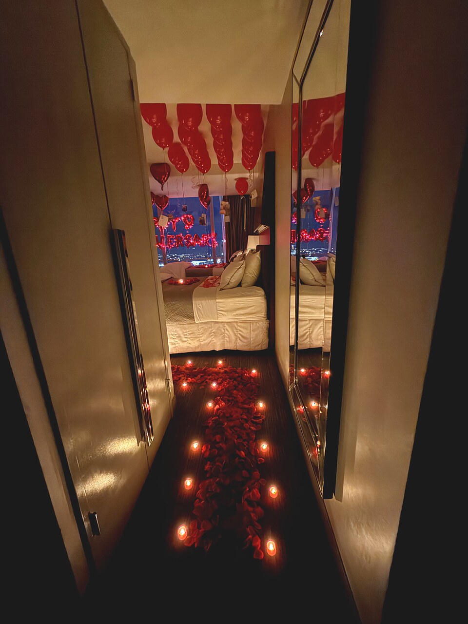 Romantic rose-petal and candle pathway leading into a decorated hotel room