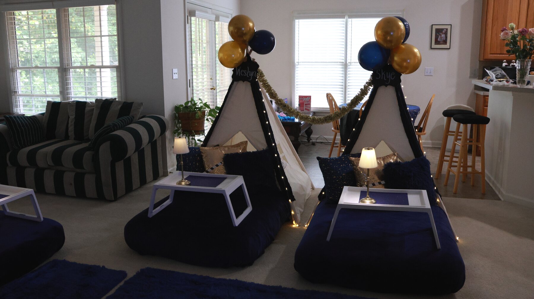 Navy-and-gold teepee party styled across a living room with seating and a dining area