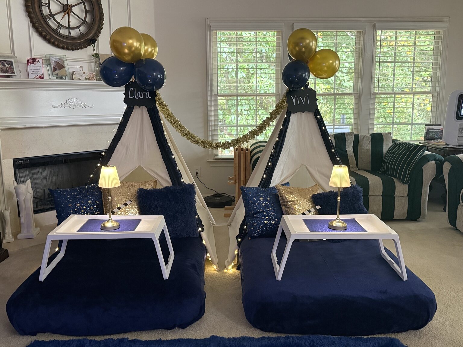 Front view of two navy-and-gold teepees with trays, lamps, and balloon names