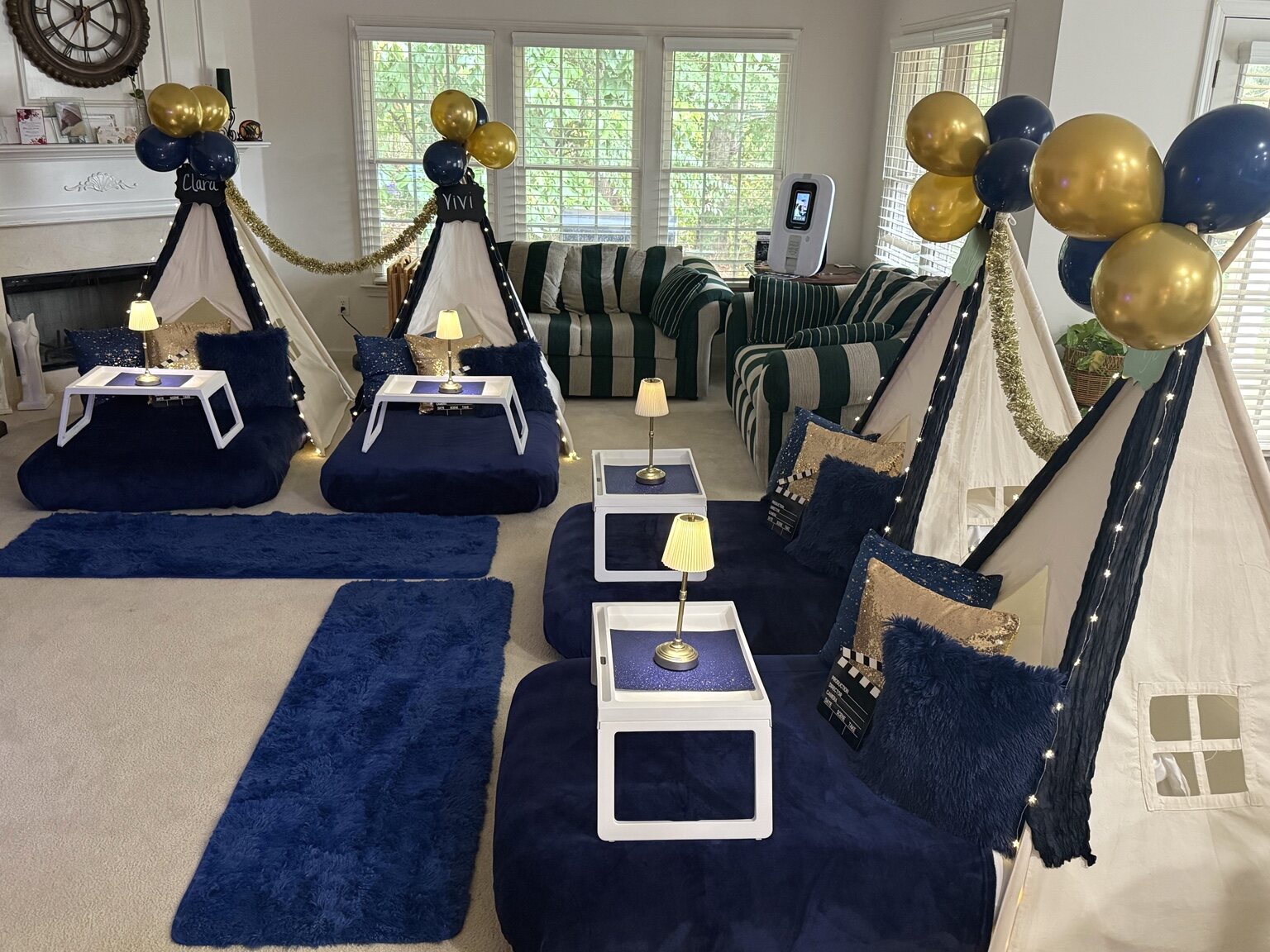 Three navy-and-gold teepees filling a living room with illuminated trays and rugs